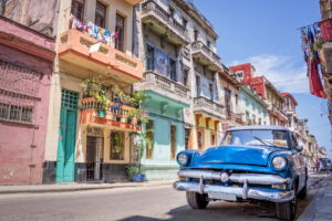 Havana | Vintage blue car parked on a street with colorful buildings | The Ultimate Travel Company