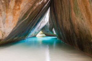 British Virgin Islands | Crystal-clear water flowing between large, smooth boulders | The Ultimate Travel Company