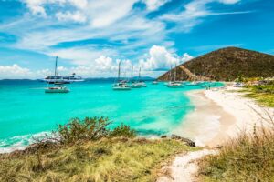 British Virgin Islands | Tropical beach with turquoise water, sailboats, and a white sand shoreline | The Ultimate Travel Company