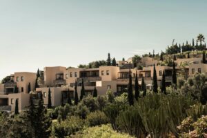 Blue Palace, Elounda, Crete | Greece | Hillside resort buildings among greenery | The Ultimate Travel Company