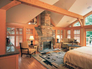 Sonora Resort, Vancouver Island | Canada | A bright bedroom with large windows, a stone fireplace, and wooden beams | The Ultimate Travel Company