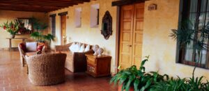 Meson De Maria | Antigua | Rustic hotel veranda with wicker furniture and lush plants | The Ultimate Travel Company