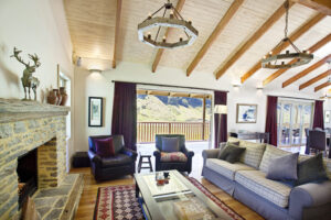 Minaret Station, New Zealand | A rustic living room with a stone fireplace, wooden beams, and mountain views | New Zealand | The Ultimate Travel Company