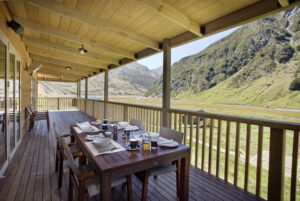 Minaret Station, New Zealand | Outdoor dining on a wooden deck with mountain views | The Ultimate Travel Company