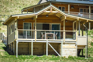 Minaret Station, New Zealand | Wooden cabin with a screened porch in a grassy landscape | The Ultimate Travel Company