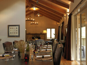 Minaret Station, New Zealand | A cozy dining area with a set table, exposed wooden beams, and a lit fireplace | New Zealand | The Ultimate Travel Company