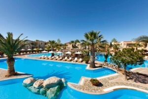 Porto Sani Village, Halkidiki | Greece | Resort swimming pool with loungers and palm trees | The Ultimate Travel Company