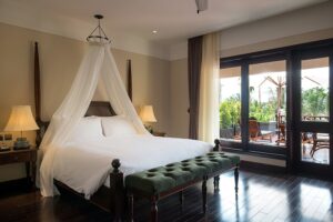La Siesta Hoi An Resort & Spa | Hoi An | Hotel room with canopy bed and balcony overlooking a tropical view | The Ultimate Travel Company