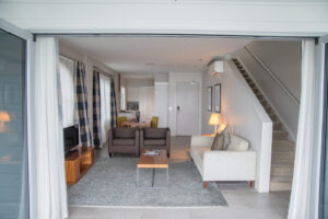 The Waterfront Suites, Bay Of Island | Open living area with sofas, stairs, and kitchenette, leading to a balcony | New Zealand | The Ultimate Travel Company