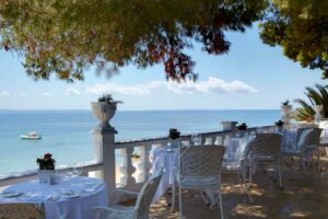 Danai Resort, Halkidiki | Greece | Seaside dining area with white chairs and tables overlooking a calm ocean | The Ultimate Travel Company