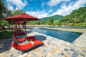 Muang La Lodge, Muang La | Infinity pool by a river.| The Ultimate Travel Company