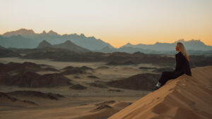 A Lady Sitting on Golden Sand Dunes | Luxury Tailor-Made Holidays | The Ultimate Travel Company