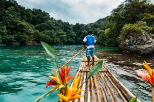 Jamaica | Man on a bamboo raft navigating a tropical river | The Ultimate Travel Company