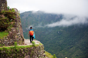 Woman Walking on the Edge of a Cliff, Machu Picchu | Luxury Peru Holidays | The Ultimate Travel Company