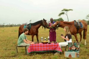 Campi Ya Kanzi, Chyulu Hills | Kenya | Couple eating together with horses | The Ultimate Travel Company