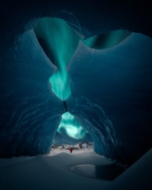 Person Walking Through an Ice Cave with the Northern Lights Above | Luxury Arctic Holidays | The Ultimate Travel Company